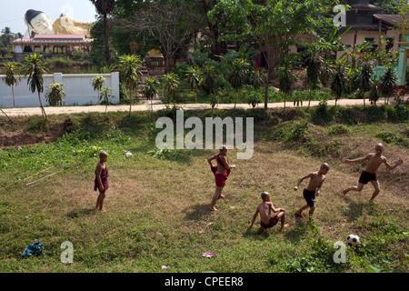 Eine Gruppe von jungen Mönche spielen Fußball auf einer unebenen Wiese außerhalb ihres Klosters in Bago, Myanmar. Stockfoto