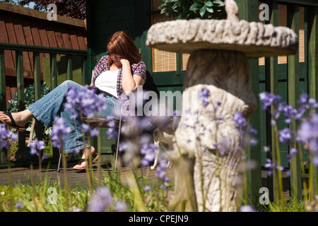 Frau liest eine Kindle e-Reader saßen draußen ihr Sommerhaus in voller Sonne. Stockfoto