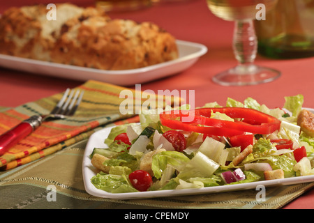 Ein gemischter Blattsalat mit Romaine, Tomaten, Zwiebeln und Paprika serviert mit Seiten von Sauerteigbrot und ein Glas Wein Stockfoto