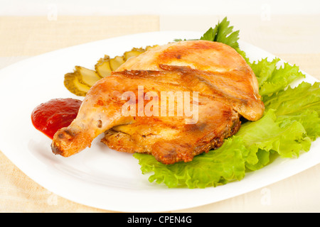 Gegrilltes Huhn auf einem Teller mit Gewürzgurken und Tomatensauce Stockfoto