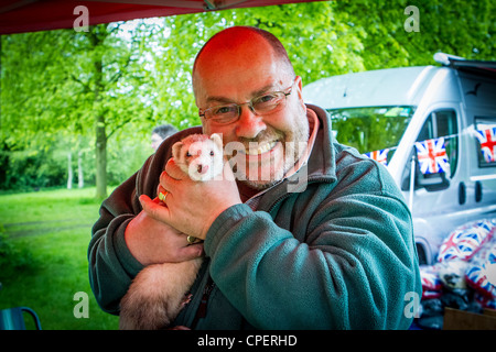 Reifer Mann gerne ein Frettchen halten die Hundeausstellung in Marbury Park, Northwich, Cheshire Stockfoto