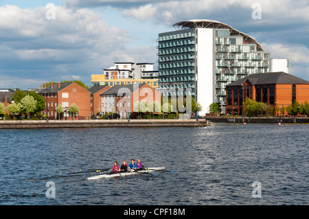 Ruderer auf den Manchester Ship Canal in Salford Quays. Abito Appartementhaus hinter.  Salford, Manchester, England, UK Stockfoto