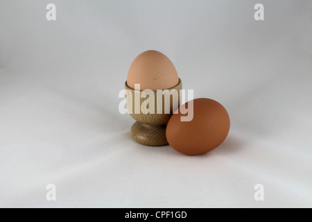 Zwei Eiern und einem hölzernen Eierbecher in ein leichtes Zelt mit weißem Hintergrund Stockfoto
