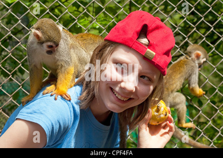 junges Mädchen mit gemeinsamen Totenkopfaffen (Saimiri Sciureus) auf dem Rücken im Serengeti-Park Hodenhagen, Niedersachsen, Deutschland Stockfoto