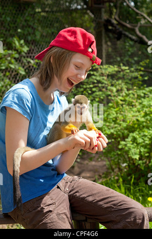 junges Mädchen mit gemeinsamen Totenkopfaffen (Saimiri Sciureus) auf dem Rücken im Serengeti-Park Hodenhagen, Niedersachsen, Deutschland Stockfoto