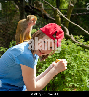 junges Mädchen mit gemeinsamen Totenkopfaffen (Saimiri Sciureus) auf dem Rücken im Serengeti-Park Hodenhagen, Niedersachsen, Deutschland Stockfoto