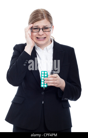 Junge Geschäftsfrau mit Kopfschmerzen, Glas mit Wasser und Tabletten. Isoliert auf weißem Hintergrund. Stockfoto