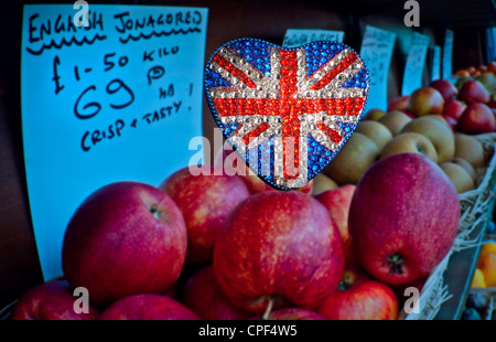 Britische Äpfel produzieren Herzförmige reflektierende Sekt Union Jack Flagge Motiv mit englischen Jonagored Äpfel auf Obst- und Gemüsehändler Display hinter Großbritannien Stockfoto