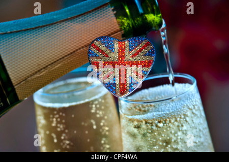 BRITISCHER SEKT mit herzförmigem funkelndem Motiv der Union Jack Flag mit Flaschen, die Gläser BRITISCH-englischen Sekt hinter Großbritannien ausschenken Stockfoto