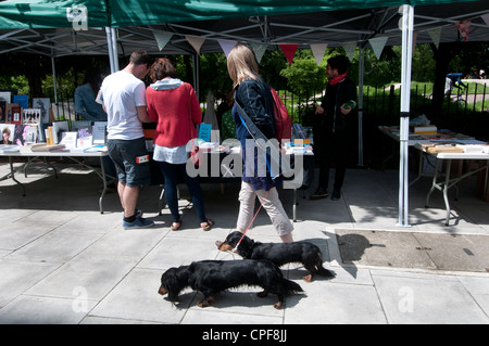 Goldschmied Zeile Hackney. Sonntagmorgen Buchmarkt. Frau mit zwei Dackel geht vorbei an Ständen Stockfoto