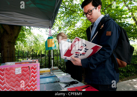 Goldschmied Zeile Hackney. Sonntagmorgen Buchmarkt. Asiatischer Mann Blick auf Buch "Kunst und Text" Stockfoto