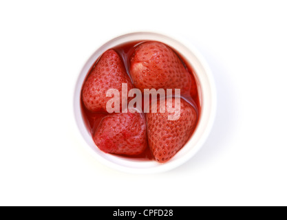 vier Erdbeeren im eigenen Saft auf dem Teller auf weißem Hintergrund Stockfoto