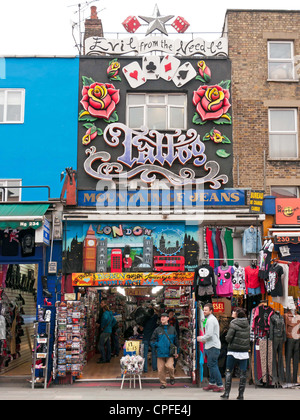 Shopping-Fans und Touristen betrachten eine Utique und Tattoo-Studio in einer Straße in Camden Market, London, UK Stockfoto