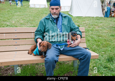 Mann mit 2 Hunden sitzen auf der Bank, Neshaminy Park, Pennsylvania, USA Stockfoto