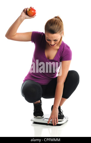 Schöne junge Frau feiert Gewichtsverlust während der Waage betreten und hält Apfel Stockfoto