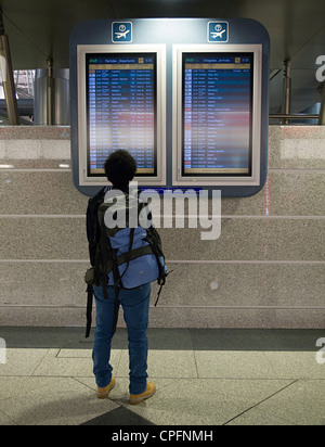 Person Blick auf Zeitplan Flugtafel in Flughafen Stockfoto