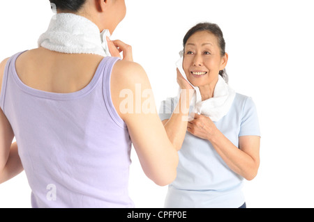 Ältere Frau und Mitte Erwachsene Frau Schweiß durch Handtuch abwischen Stockfoto