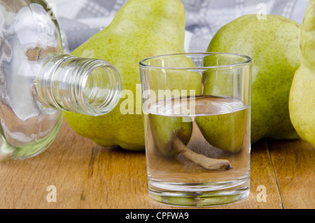 Obstbrände in ein Glas und frische Birnen im Hintergrund Stockfoto