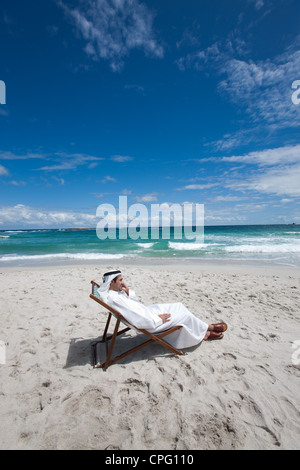Arabische Mann auf dem Handy sitzen am Strand. Stockfoto