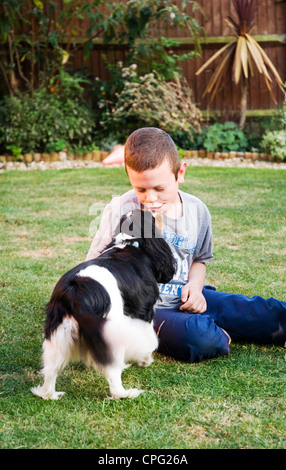 Ein kleiner Junge küssen einen Hund im Garten Stockfoto