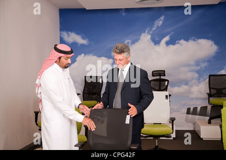 Verkäufer, die Unterstützung der Arabische Mann für Bürostühle im Möbelhaus einkaufen. Stockfoto