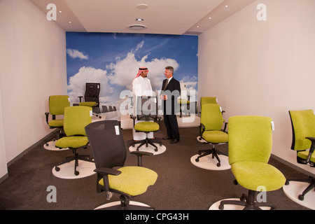 Verkäufer, die Unterstützung der Arabische Mann für Bürostühle im Möbelhaus einkaufen. Stockfoto