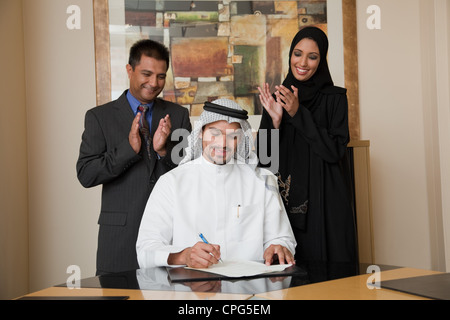 Arabische Geschäftsmann unterschreiben, zwei Kollegen klatschte auf der Seite. Stockfoto