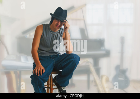 Young blues Spieler während einer Jam-Session-Pause, sitzen auf einem Hocker tragen einen schwarzen Fedora ruht. Stockfoto