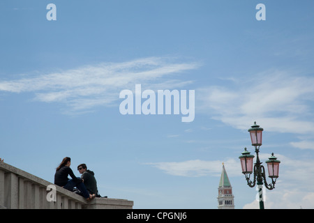 Ein junges Paar sitzt auf einer Brücke Unterführung in der Nähe von St. Marks Platz in Venedig, Italien. Stockfoto