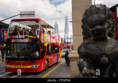 Männlicher Löwe aus Bronze Statue bewacht das Tor zum Fangbang Straße Old Street mit roten Touristenbus Tour in Shanghai Peoples Republic Of China Stockfoto