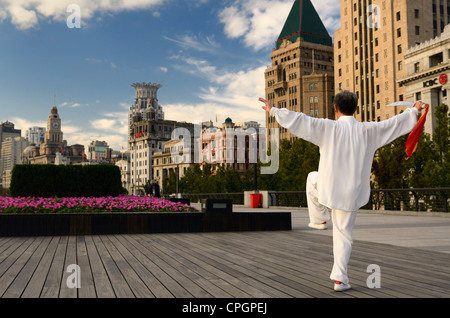 Mann in Weiß mit Tai Chi Schwert Ausübung auf den Bund in der Morgendämmerung in Shanghai, China Stockfoto