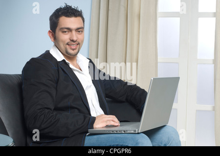 Junger Mann, sitzend mit Laptop, Porträt Stockfoto
