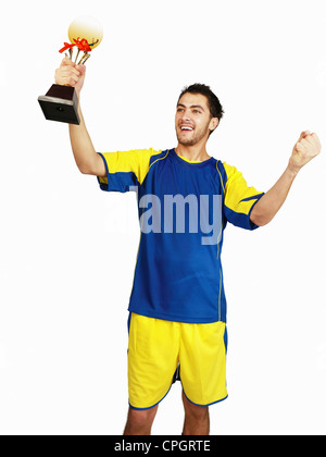 Junger Mann, der Trophäe, hält lächelnd Stockfoto
