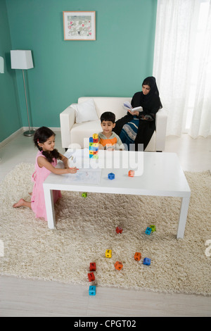 Arabische Mutter lesen, Kinder spielen zu Hause Stockfoto