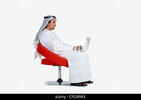 Junger Mann sitzt auf einem Stuhl, mit laptop Stockfoto