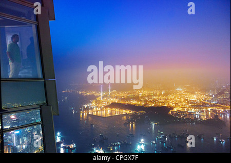 Ein Mann schaut auf Kowloon in der Nacht vom International Commerce Centre Stockfoto