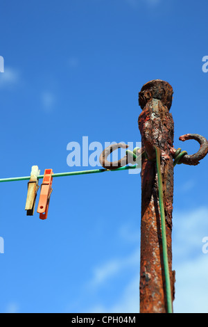 Alte rostige Kleidung Pole und zwei Wäscheklammern an einem Kunststoff Seil vor blauem Himmel Stockfoto