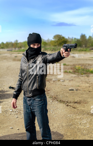 Maskierten bewaffneten Umweltgifte mit einer Pistole Stockfoto