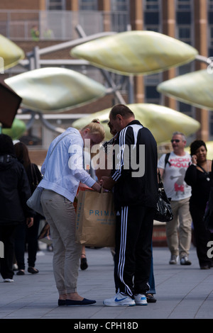 Shopper pause auf der belebten Gehweg der Westfield Stratford Mall, Einkäufe bei Primark zu überprüfen. Stockfoto