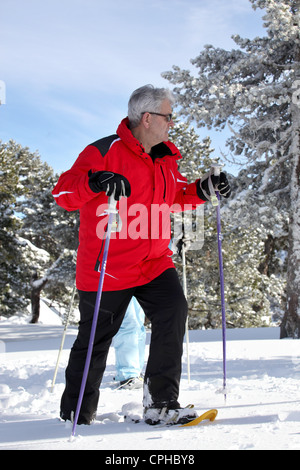 Älterer Mann zu Fuß in Schneeschuhen Stockfoto