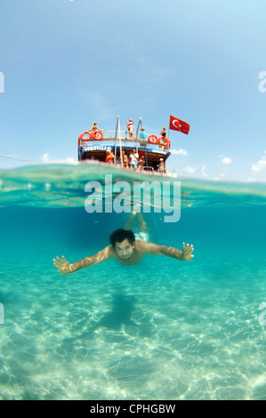 Split Level, Mann tauchen neben dem Tourenboot, Cleopatra Island (Cedar Island), Ägäis, Türkei Stockfoto