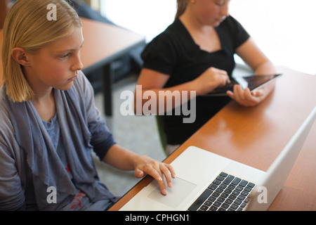 Zwei mittlere Schulmädchen mit Technologie im Klassenzimmer; Laptop und Ipad. Stockfoto