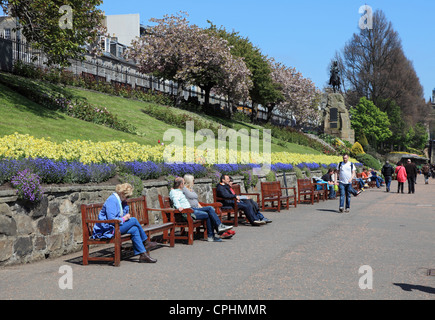 Menschen zu Fuß und sitzen auf Bänken in der Princes Street Gardens Edinburgh Schottland Großbritannien Stockfoto