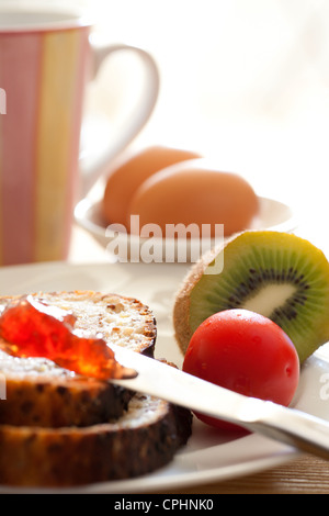 Frühstück mit Brot Jam Eiern Cherry Tomaten Kiwi und Tee Kaffee Stockfoto