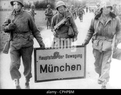 Amerikanische Soldaten marschieren in München tragen das Ortsschild (Überschrift "München - Hauptstadt der Bewegung"), München, 30. April 1945, Stockfoto