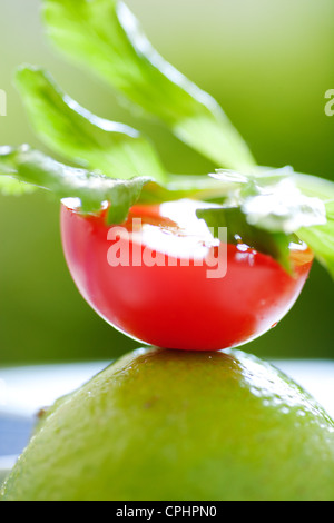 Die Hälfte in Scheiben geschnitten Red Tomato ruht auf geschnittene Limetten mit Koriander-Blättern an der Spitze Stockfoto
