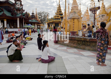 Myanmar, Burma. Shwedagon-Pagode, Yangon, Rangun. Gläubige beten im Rathaushof Stupa. Stockfoto