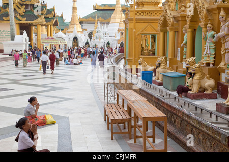 Shwedagon-Pagode, Yangon.  Frauen beten zu Nats, verehrt buddhistischen Geistern in Myanmar, als Besucher umrunden die Stupa. Stockfoto