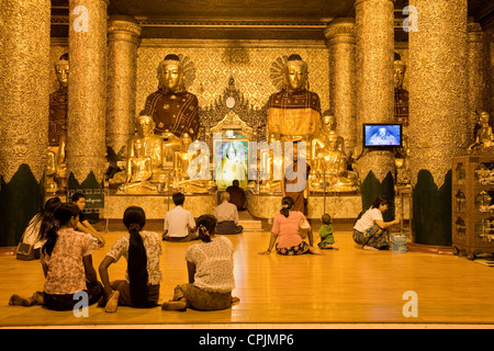 Myanmar, Burma. Shwedagon-Pagode, Yangon, Rangun. Abends leuchtet Illuminate Gläubige beten in einem buddhistischen Schrein. Stockfoto