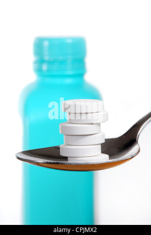 Antacidum Tabletten auf einem Löffel, eine Flasche von Antazida verschwommen im Hintergrund Stockfoto